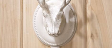 A wall-mounted deer head decoration above a white towel ring.