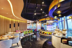 A modern restaurant with a curved counter, colorful chairs, and a bar area. - Aloft Guangzhou Tianhe (Guangzhou)