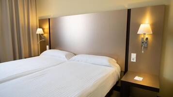 Une chambre d’hôtel avec un lit double, deux lampes de chevet, une table de chevet et un rideau.