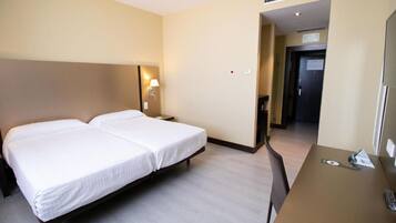 Habitació d'hotel amb dos llits, un escriptori i una cadira.