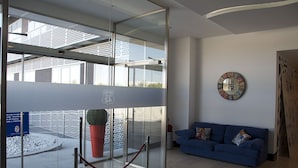 A modern lobby with a glass partition, a blue sofa, and a clock on the wall. - Hotel Route 42 (Illescas)