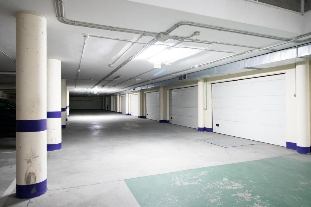 A parking garage with white and blue pillars, concrete floor, and white garage doors.