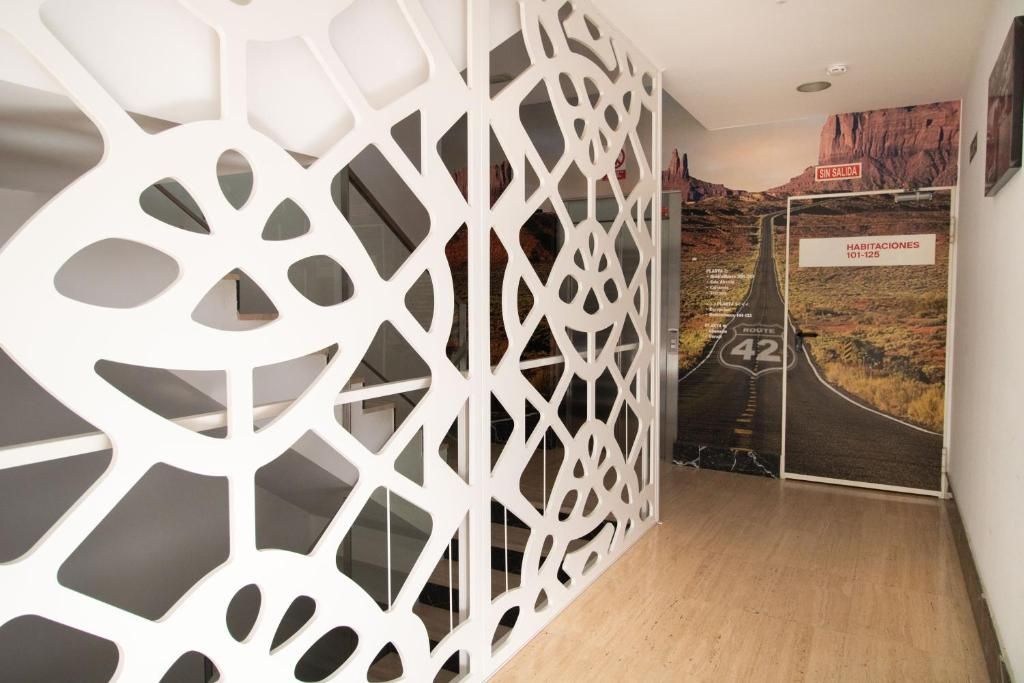 A hallway with a white decorative partition, a sign for room numbers 101-125, and a wall mural depicting a desert landscape.