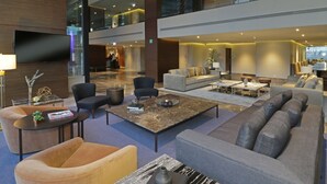 A spacious lobby with multiple seating areas, a flat-screen TV mounted on the wall, and a reception desk in the background. - Holiday Inn Express & Suites Monterrey Valle by IHG (San Pedro Garza García)