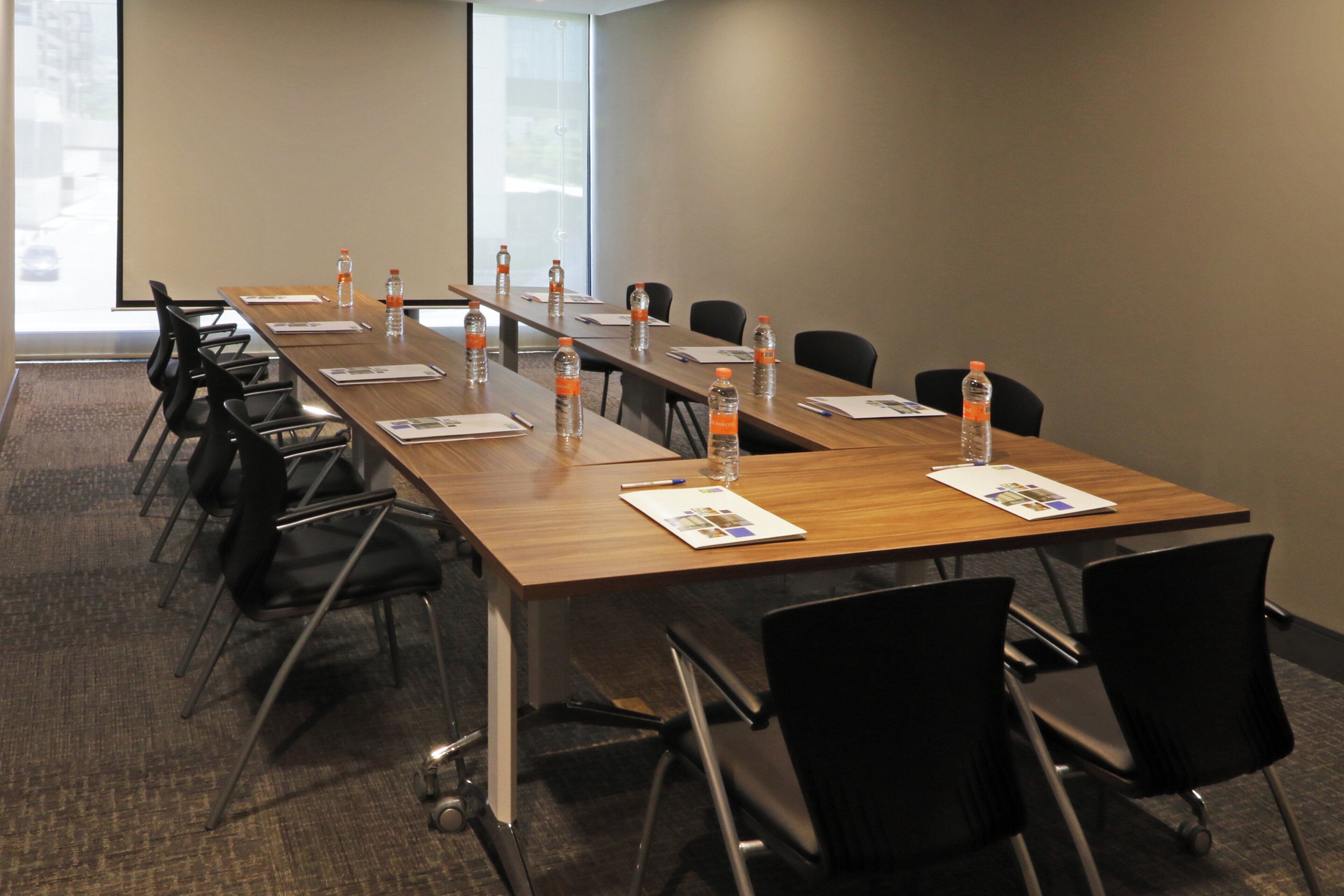 A conference room with a long table, chairs, water bottles, and presentation materials.