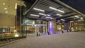 A modern hotel entrance with a glass facade, a covered outdoor area, and a well-lit walkway. - Holiday Inn Express & Suites Monterrey Valle by IHG (San Pedro Garza García)