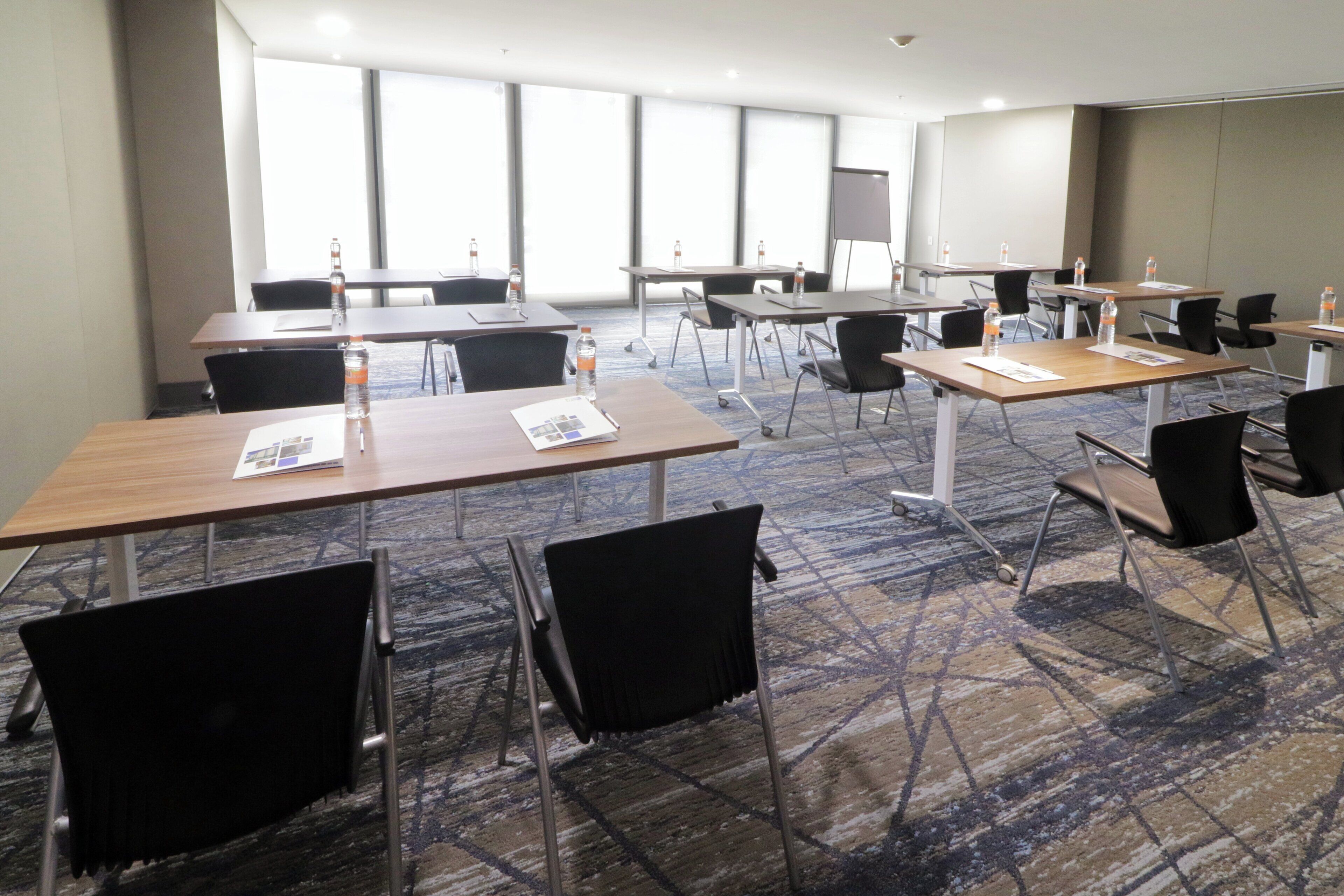 A conference room with tables, chairs, and water bottles.