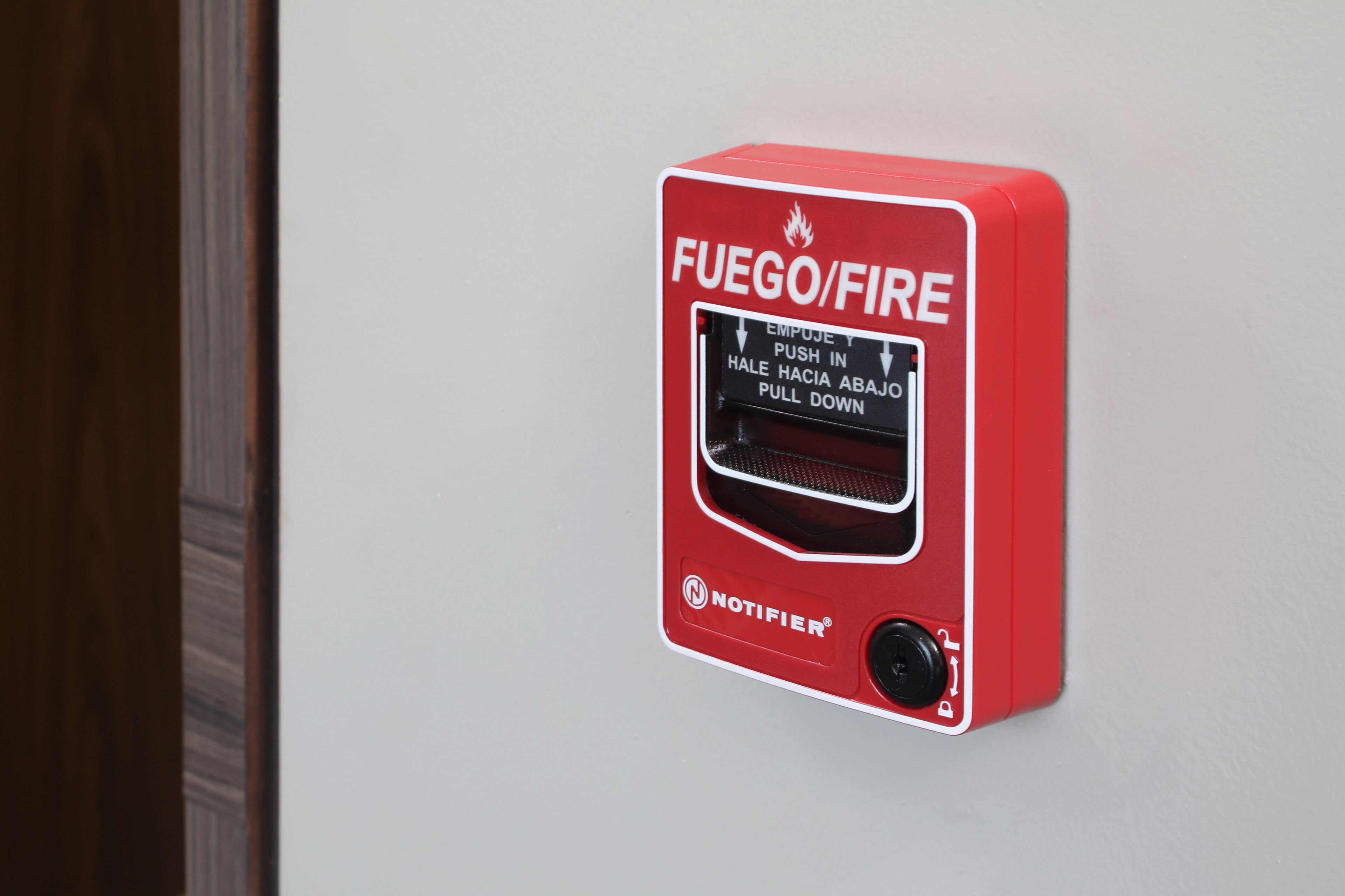 Une sonnette d’alarme incendie rouge, avec des instructions rédigées en plusieurs langues.