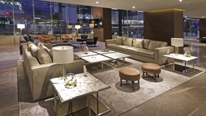 A modern hotel lobby with leather sofas, marble coffee tables, and a large window offering a city view. - Holiday Inn Express & Suites Monterrey Valle by IHG (San Pedro Garza García)