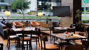 A restaurant with a modern interior, featuring leather seating, wooden tables, and a large TV screen on the wall. - Holiday Inn Express & Suites Monterrey Valle by IHG (San Pedro Garza García)