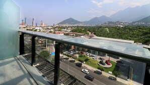 A cityscape with mountains in the background, a parking lot with cars, and a building with a glass balcony. - Holiday Inn Express & Suites Monterrey Valle by IHG (San Pedro Garza García)