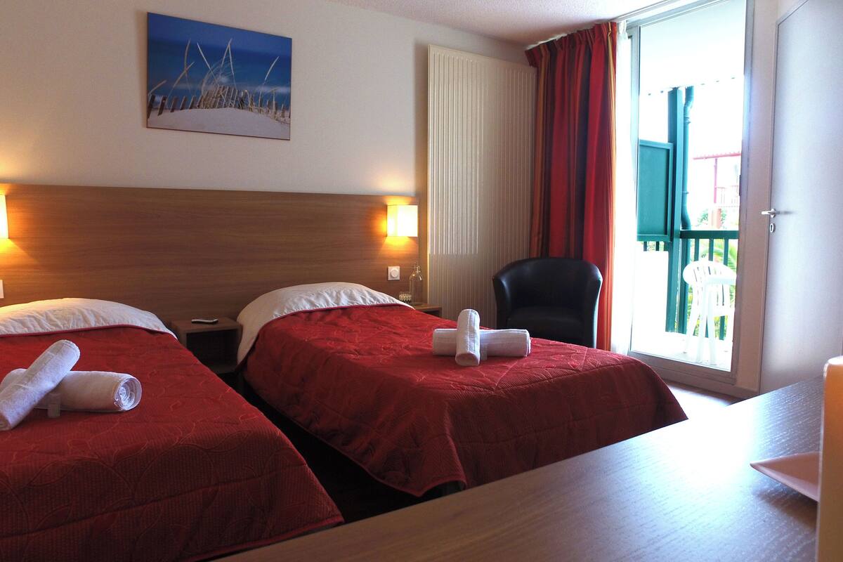 Habitación de hotel con dos camas, un cuadro en la pared, una silla y una mesa.