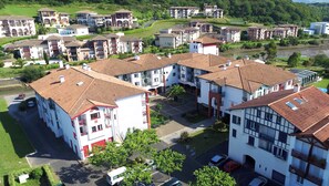 Un quartier résidentiel composé de plusieurs immeubles à deux étages, avec une cour centrale et une rivière en arrière-plan.