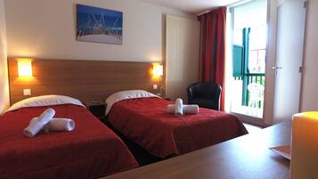 Habitación de hotel con dos camas, un cuadro en la pared, una silla y una mesa.