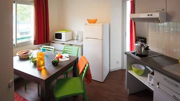 Cocina compacta con mesa, sillas, refrigerador, microondas y lavaplatos.