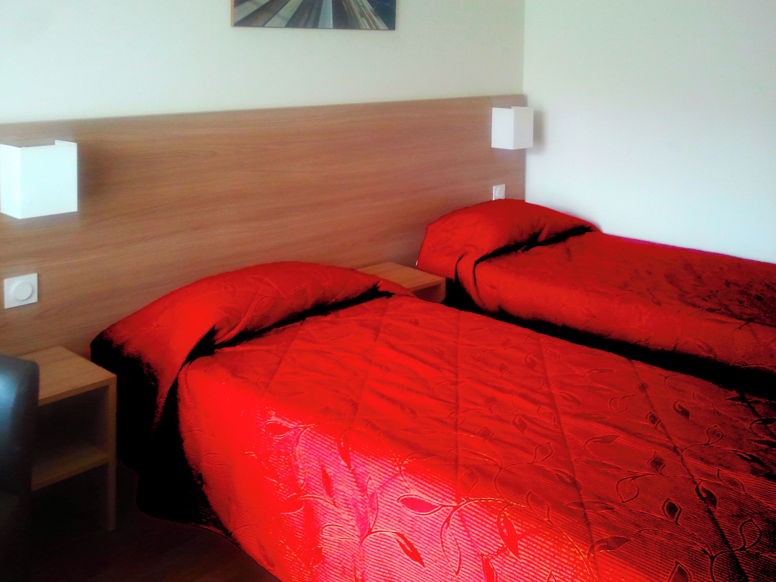 A hotel room with two beds, wooden headboards, and bedside lamps.