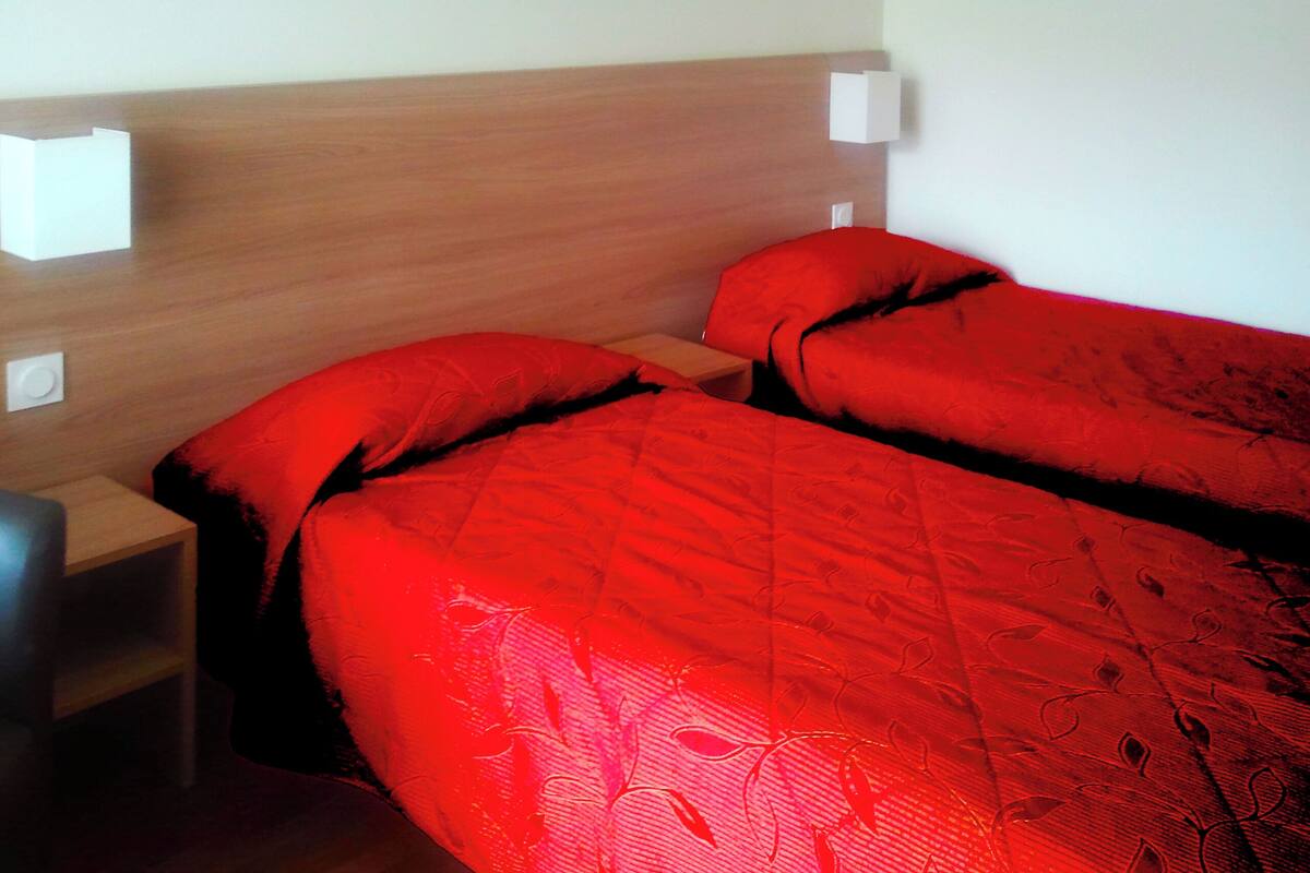 Una habitación de hotel con dos camas, cabeceros de madera y lámparas de noche.