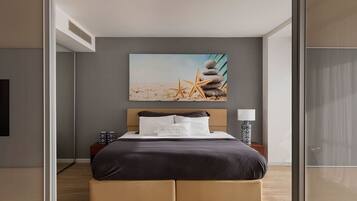 A modern hotel room with a bed, a nightstand, a lamp, and a beach-themed artwork on the wall.