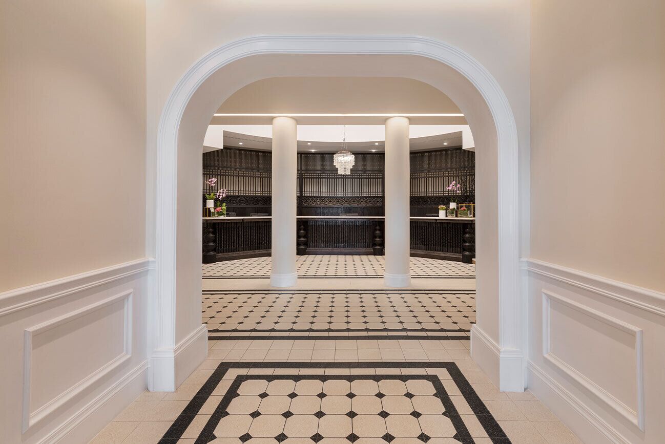 A hotel lobby with a checkered floor, white columns, and a chandelier.