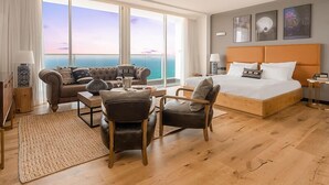 A hotel room with a large bed, a sofa, a chair, a coffee table, and a view of the ocean. - Resort Hadera Hotel By Jacob (Hadera)