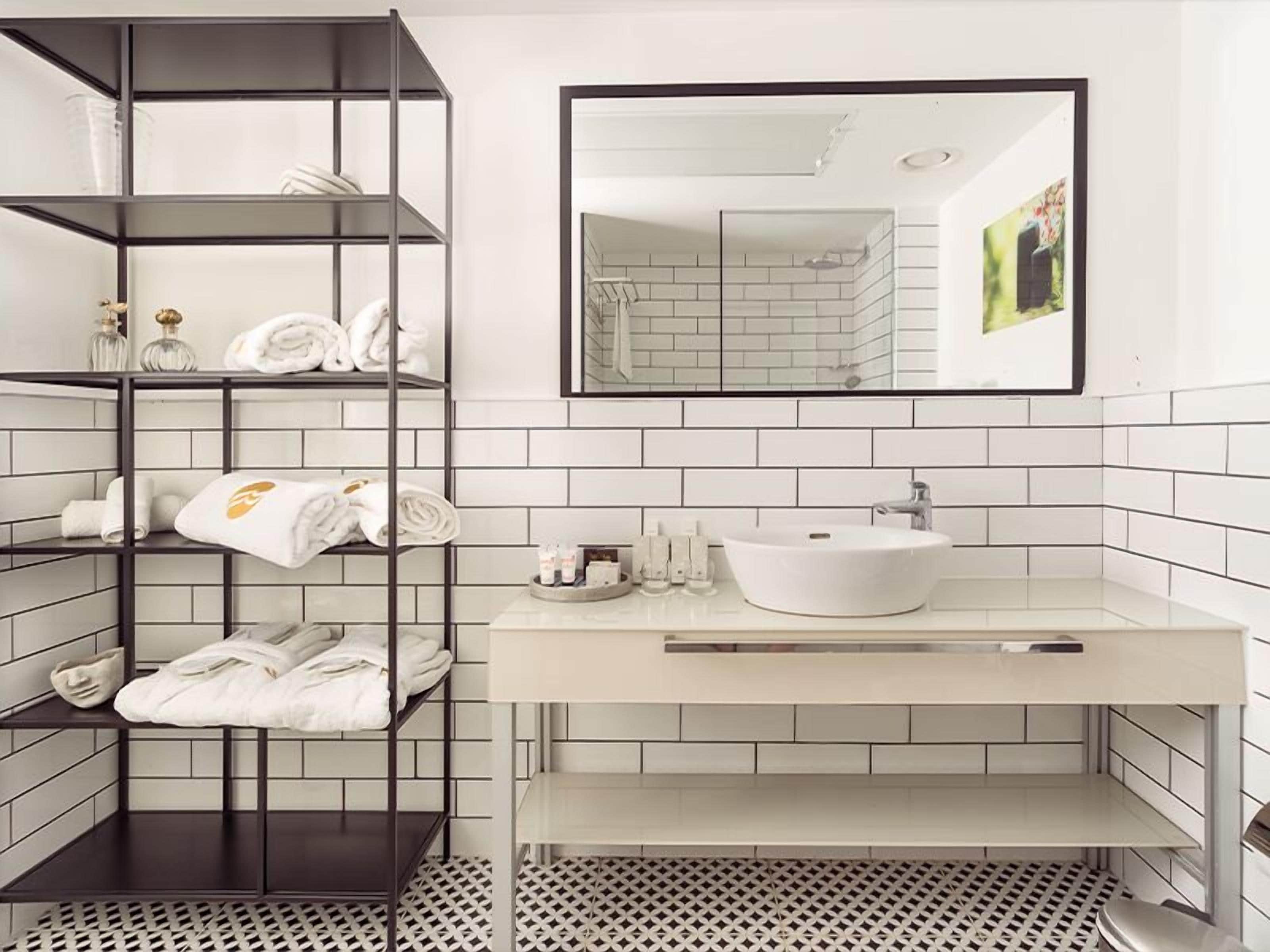 Un baño con un lavabo blanco, un espejo, un perchero para toallas y un suelo estampado.