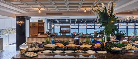 Una mesa de buffet con diversas opciones de comida, un centro de mesa con una planta grande y un diseño moderno en el techo.