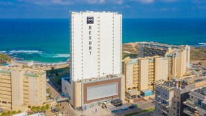 A tall building labeled 'RESORT' with a view of the ocean and beach. - Resort Hadera Hotel By Jacob (Hadera)