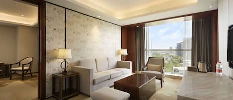 Ein modernes Hotelzimmer mit einer Couch, Sesseln, einem Couchtisch und Blick auf die Stadt.