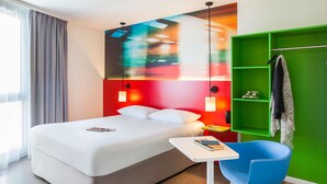 Una habitación de hotel moderna con cama, mesita de noche y un armario verde.
