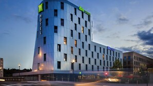Un hotel moderno con fachada curva, múltiples ventanas y un llamativo letrero de 'ibis Styles'.