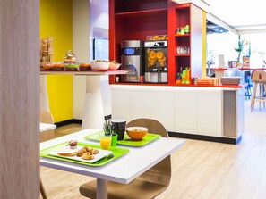 A breakfast setup with croissants, orange juice, and a bowl of cereal on a white table with green placemats. - Ibis Styles Mulhouse Centre Gare (Mulhouse)