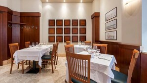 A restaurant with multiple tables and chairs, a stone floor, and framed pictures on the wall.