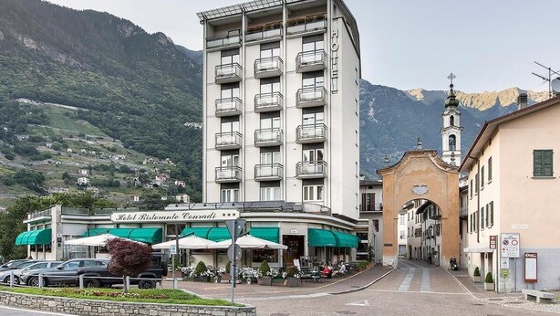 A hotel with a central courtyard, a bell tower, and a mountain backdrop.