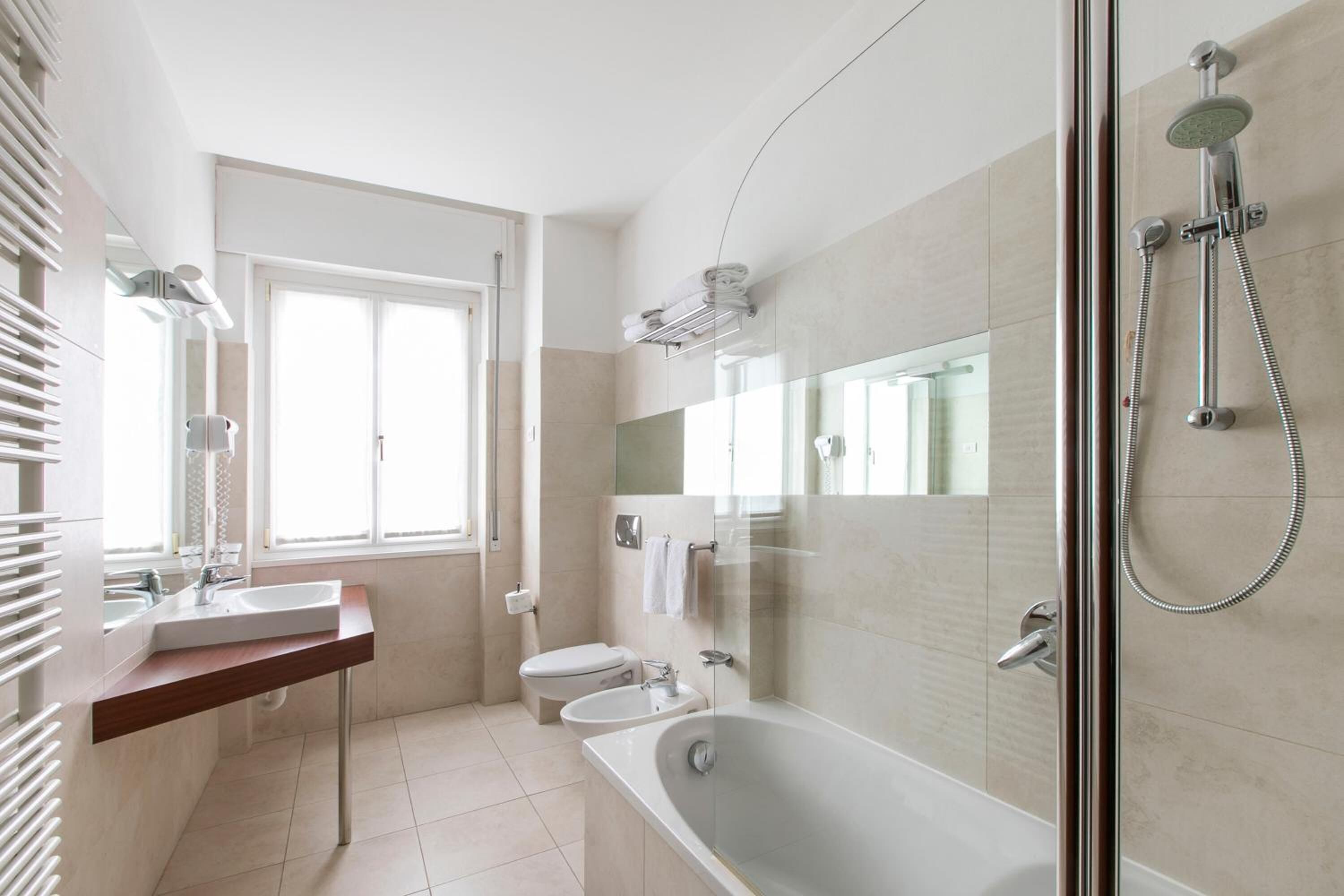 Un baño moderno con ducha de vidrio, bañera independiente y retrete.