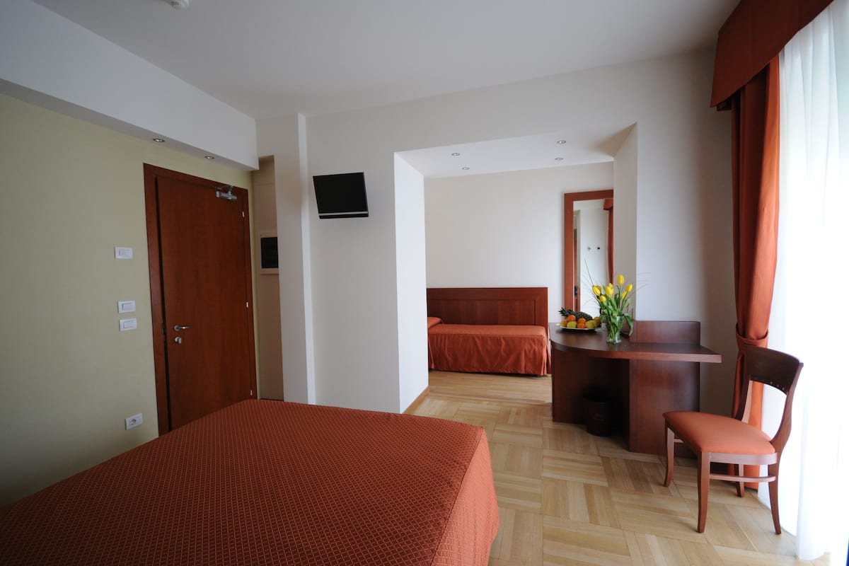 Une chambre d’hôtel comprenant un lit, un bureau avec une chaise, une télévision et un coin repas avec une table et des chaises.