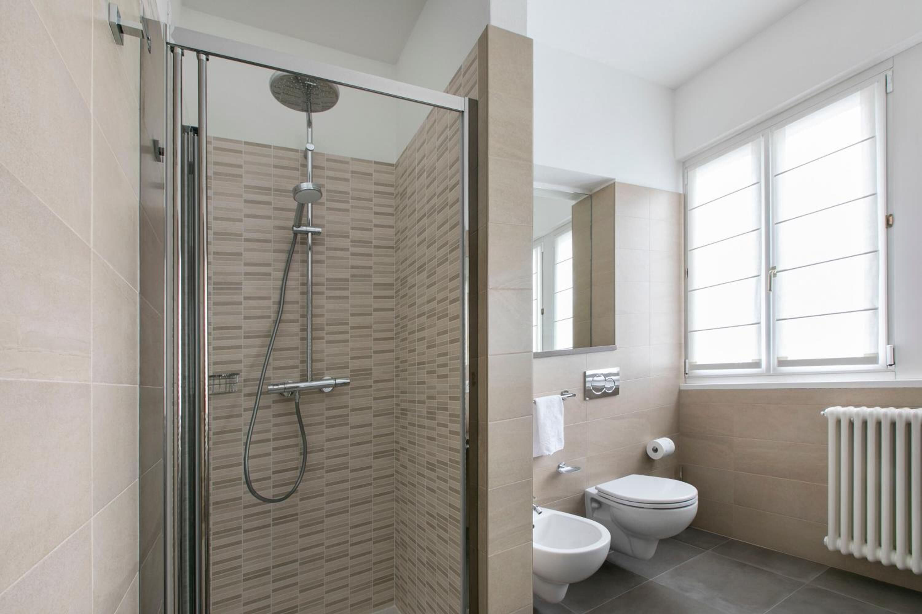 Een moderne badkamer met een douchecabine van glas, een toilet en een bidet.