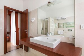 Bathroom features a large sink, mirror, and shower area with a hairdryer nearby.