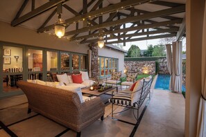 Un espace de détente intérieur accueillant, avec des meubles en osier, un mur en pierre et une vue sur une piscine.