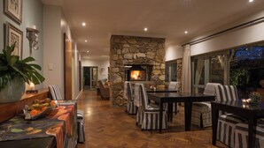 Un interior acogedor con chimenea de piedra, suelo de madera y sillas a rayas alrededor de una mesa de comedor.