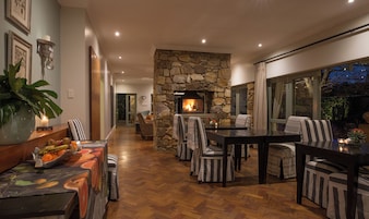 Un interior acogedor con chimenea de piedra, suelo de madera y sillas a rayas alrededor de una mesa de comedor.