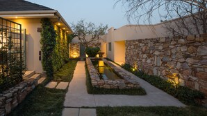 Una casa moderna con un muro de piedra, un estrecho sendero y una pequeña fuente de agua.