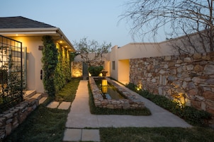 Una casa moderna con un muro de piedra, un estrecho sendero y una pequeña fuente de agua.