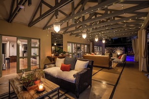 An outdoor seating area with wicker furniture, a wooden table with a candle, and string lights.
