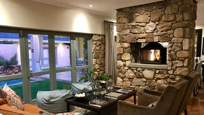 Una sala de estar acogedora con chimenea de piedra, asientos cómodos y amplias ventanas que ofrecen vistas al exterior.