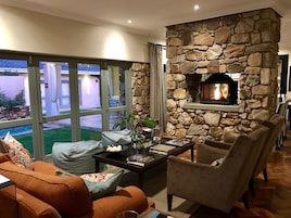 Una sala de estar acogedora con chimenea de piedra, asientos cómodos y amplias ventanas que ofrecen vistas al exterior.