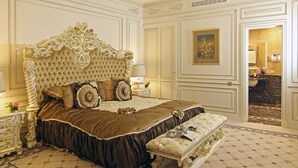 Een luxueuze slaapkamer met een gebordureerd hoofdeinde, versierde beddengoed en een klassiek design.