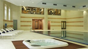Een hotel lobby met een groot overdekt zwembad, lounge fauteuils en een jacuzzi.