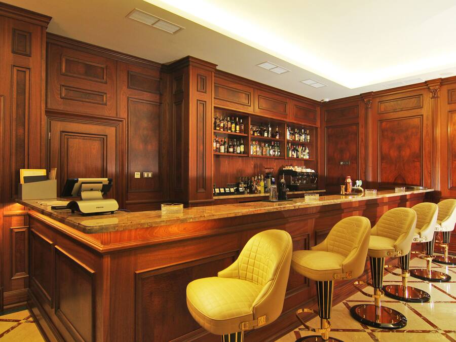 Un espace bar avec des meubles en bois, une caisse enregistreuse et des tabourets de bar.