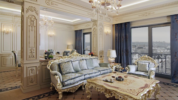 Een luxe kamer met rijk versierde details, een weelderige kroonluchter en uitzicht vanaf een balkon.