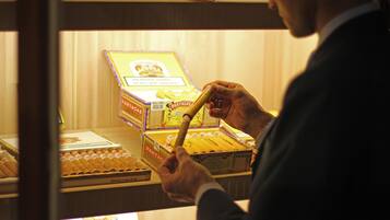 A person selecting a cigar from a display case containing various cigar brands.
